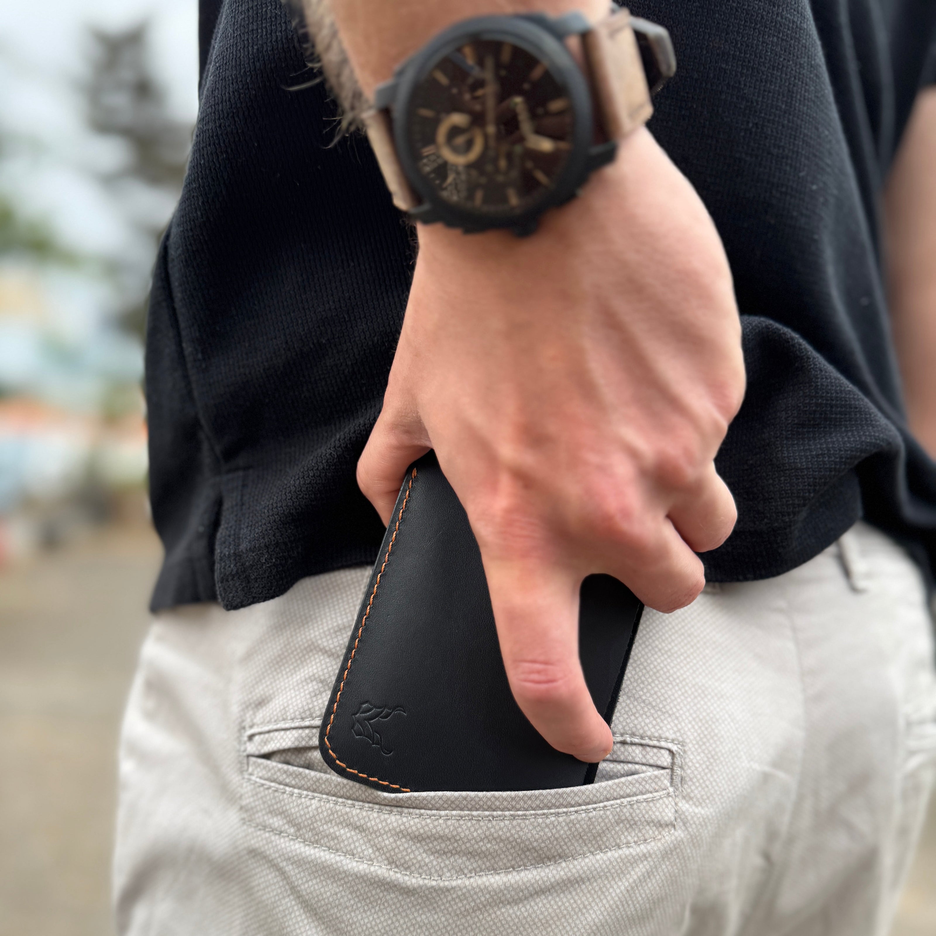 Person wearing a markore hunza fold black leather wallet in their pocket with a blurred background