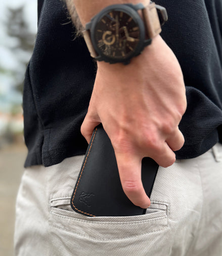 Person wearing a markore hunza fold black leather wallet in their pocket with a blurred background