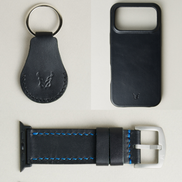 Three premium leather items for apple products in midnight black: airtag keychain with metal key ring and embossed Markore logo, iphone 17 case with embossed Markore logo and watch strap handstitched in blue with silver metal buckle and black adapter.