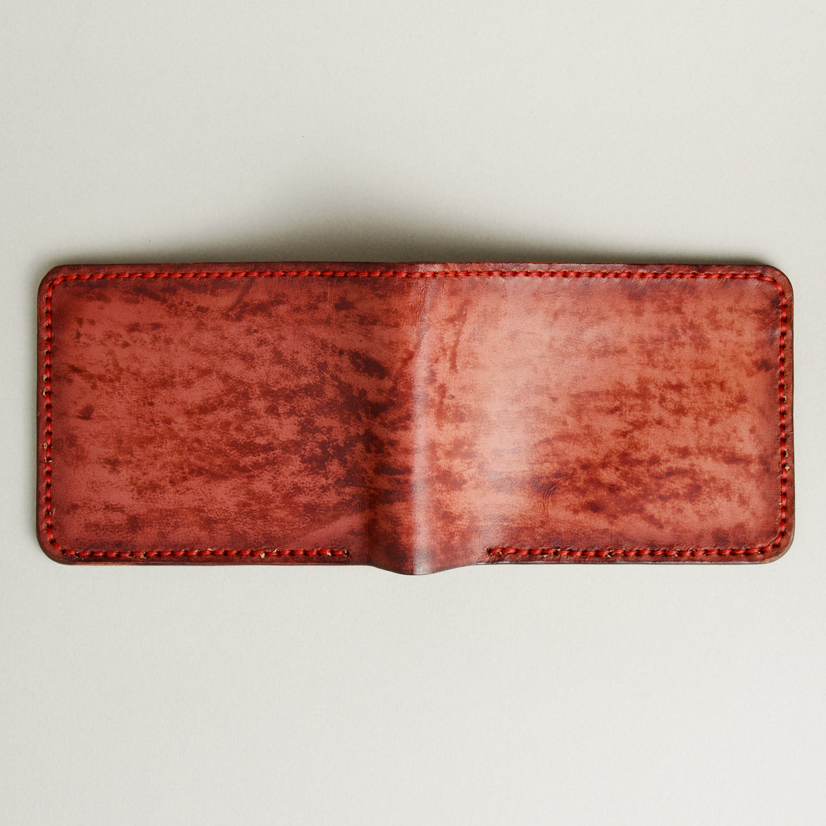 Unfolded outside view of hand-painted full-grain leather bifold wallet in red, featuring handmade stitching. Markore Canvas Flame.