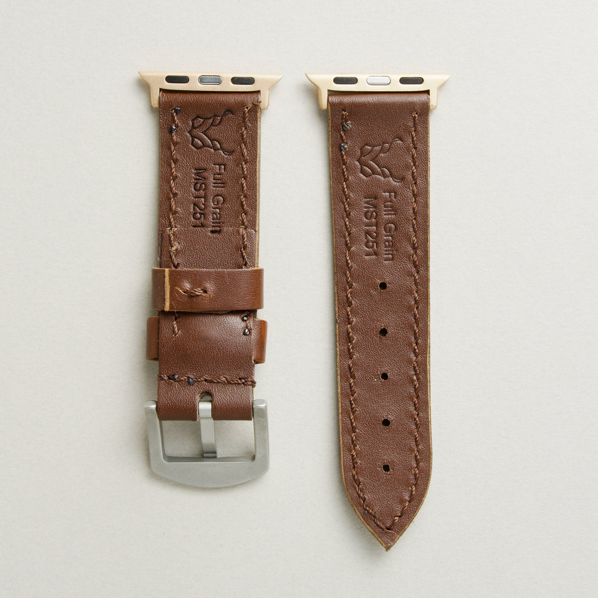 Back view of espresso brown leather strap with rose gold stainless steel adapters and silver buckle, showing handmade stitching, embossed logo, and serial number. Markore Hour Line.