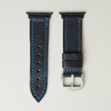 Midnight Black full-grain leather watch strap with black stainless steel adapters and silver buckle, featuring blue handmade stitching and matching blue loops. Markore Hour Line.