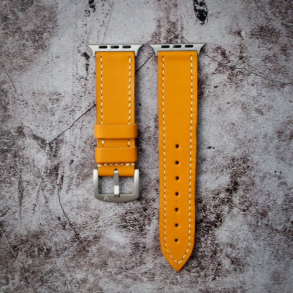 Indian Yellow leather watch strap with silver buckle on a plain gray surface