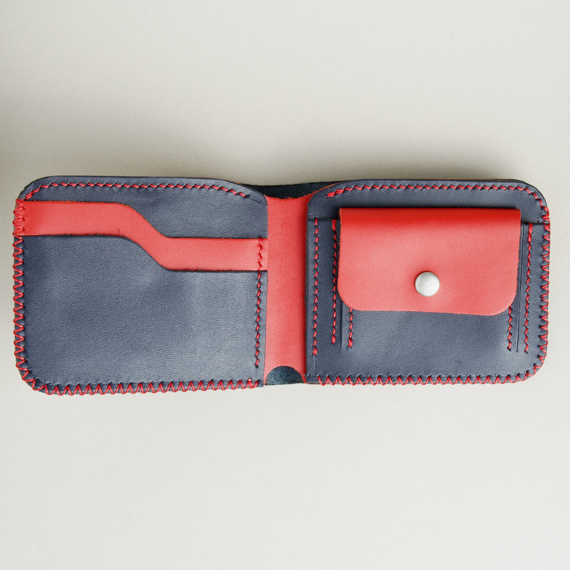 Open view of Dark Blue and Red full-grain leather bifold wallet featuring card slots, coin pocket with stainless steel press stud, and hand-stitched detailing. Markore Hunza Edge.