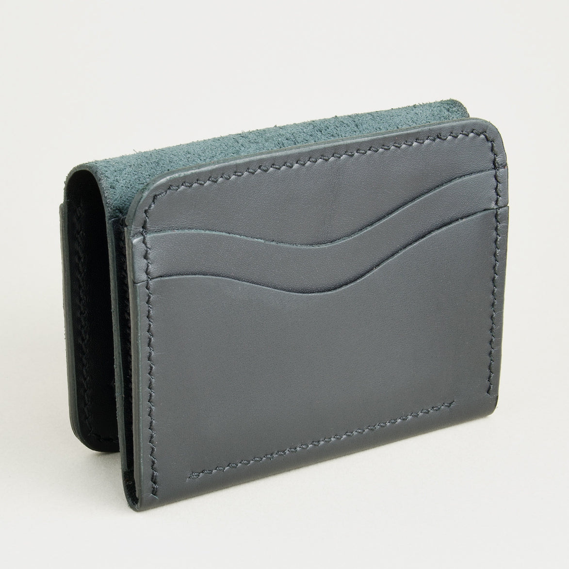 Opened side view of midnight black full-grain leather flap fold wallet featuring a flap closure, card slots and handmade stitching. Markore Khaas Andaz.