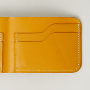 Detail of full grain leather bifold wallet in amber, featuring ivory handmade stitching card slots. Markore Hunza Fold.