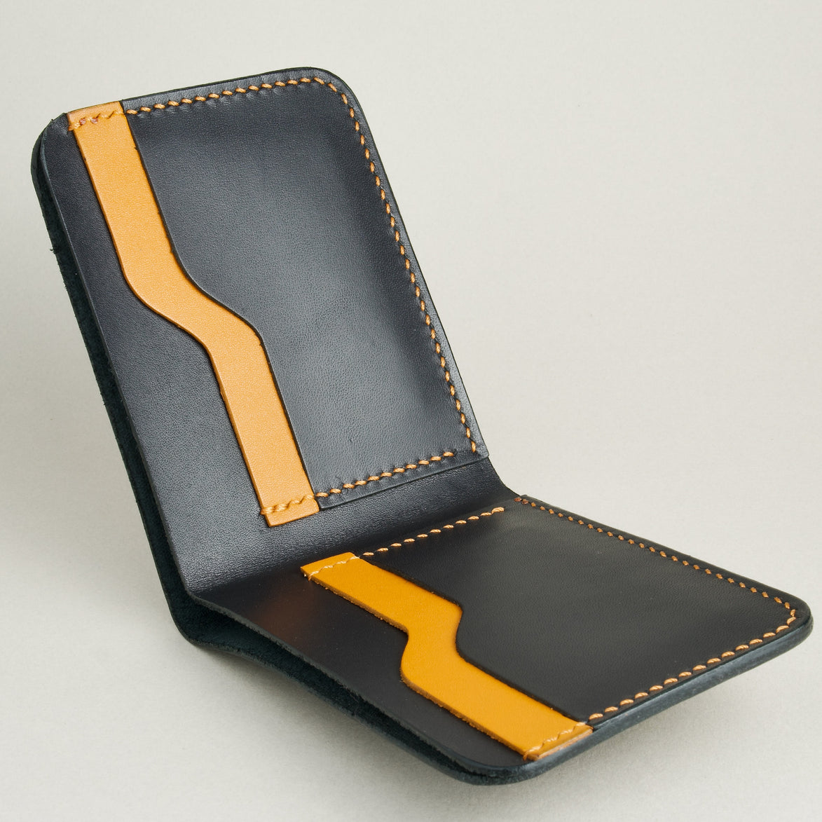 Inside view of full grain leather bifold wallet in midnight black, featuring handmade stitching and card slots in amber. Markore Hunza Fold.