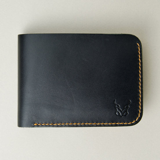 Front view of full grain leather bifold wallet in midnight black, featuring amber handmade stitching and embossed logo. Markore Hunza Fold.