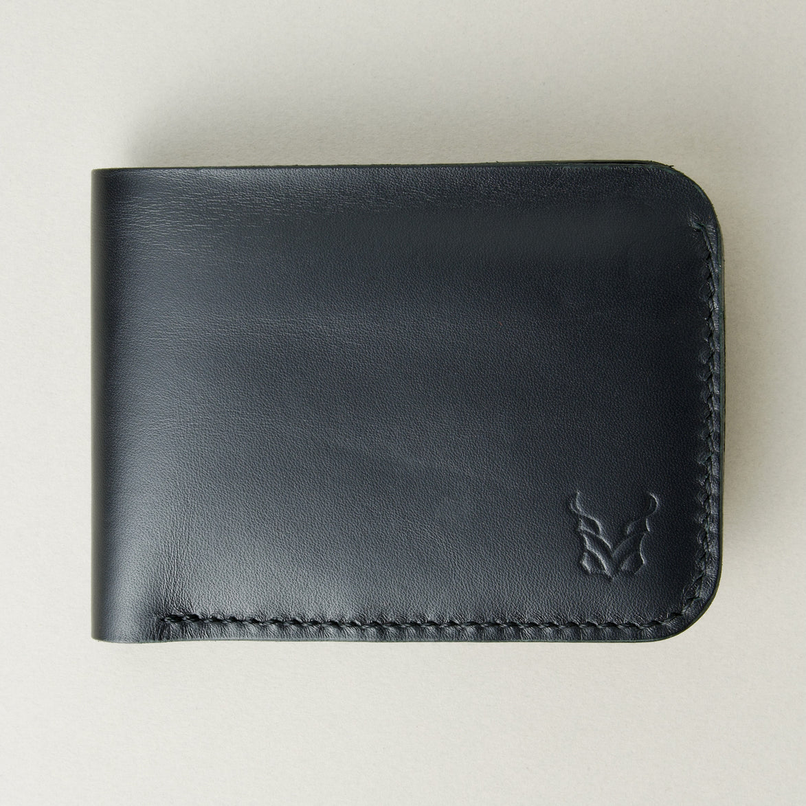 Front view of full grain leather bifold wallet in midnight black featuring handmade stitching and embossed logo. Markore Hunza Fold.