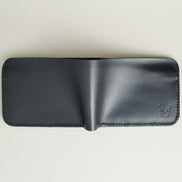 Outside view of full grain leather bifold wallet in midnight black, featuring handmade stitching and embossed logo. Markore Hunza Fold.