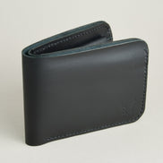 Side view of full grain leather bifold wallet in midnight black featuring handmade stitching and embossed logo. Markore Hunza Fold.