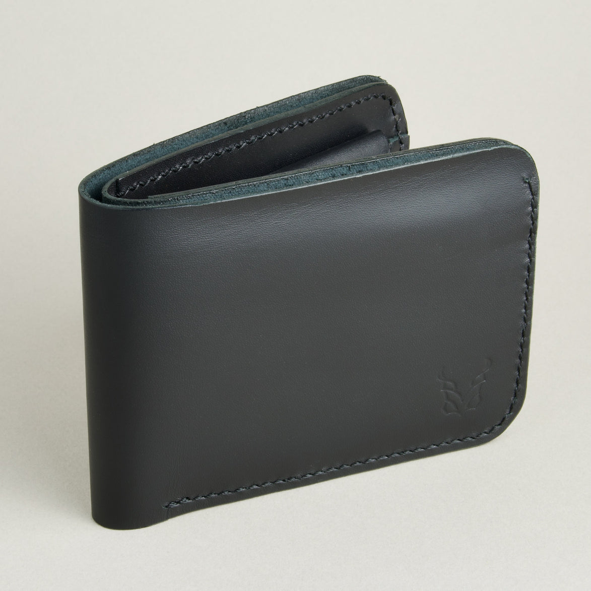 Side view of full grain leather bifold wallet in midnight black featuring handmade stitching and embossed logo. Markore Hunza Fold.