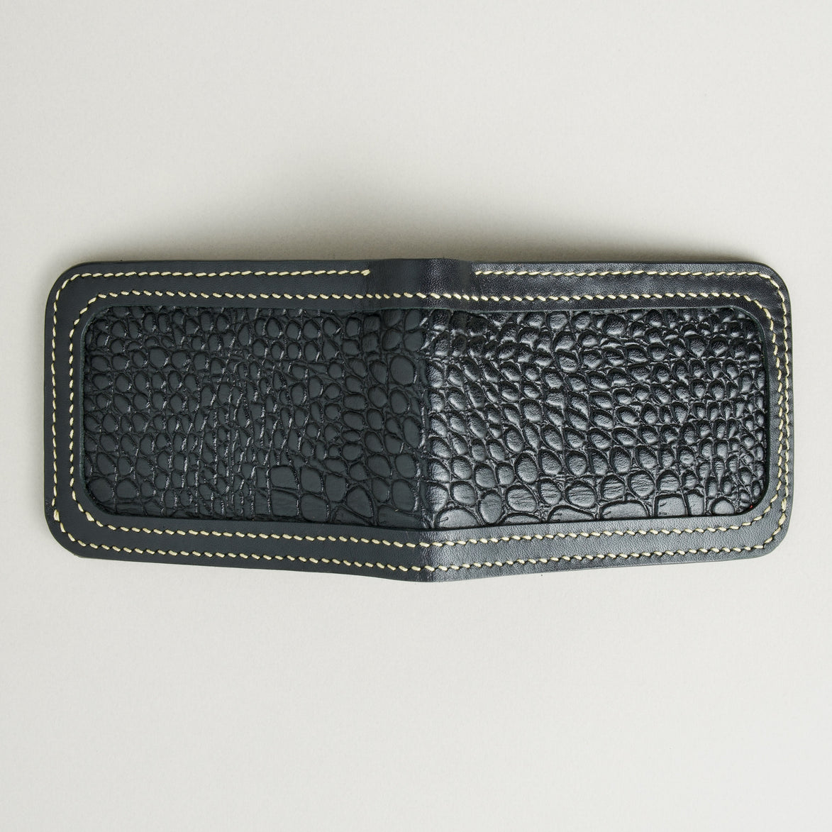 Outside view of obsidian black croc-embossed full-grain leather bifold wallet featuring ivory handmade stitching. Markore Indus Sultan