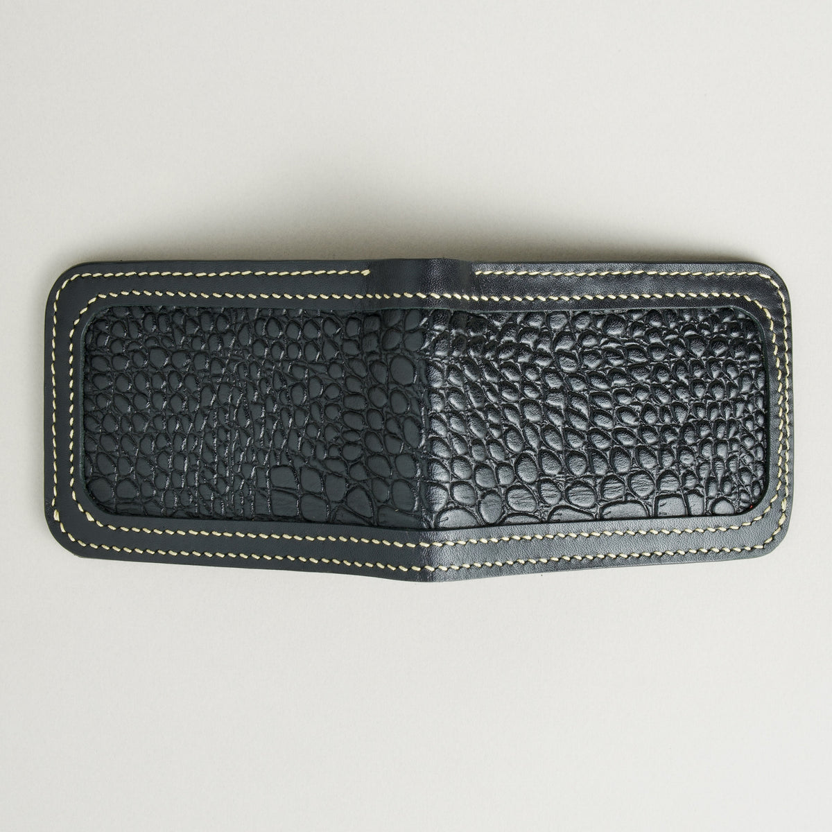 Outside view of obsidian black croc-embossed full-grain leather bifold wallet featuring ivory handmade stitching. Markore Indus Sultan