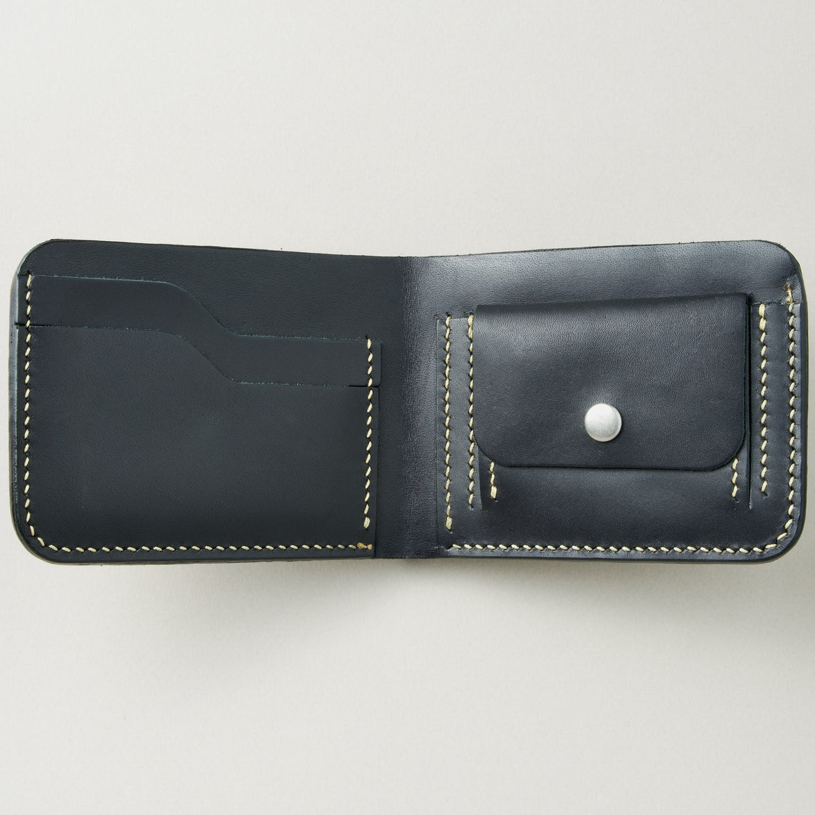 Interior view of obsidian black full-grain leather bifold wallet featuring ivory handmade stitching, card slots and coin pocket with stainless steel press stud. Markore Indus Sultan