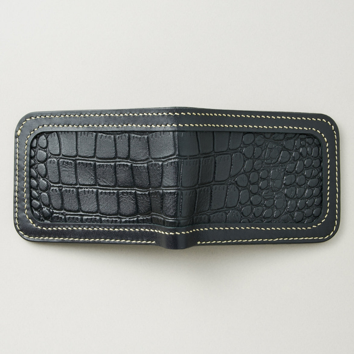 Outside view of obsidian black croc-embossed full-grain leather bifold wallet featuring ivory handmade stitching. Markore Indus Sultan