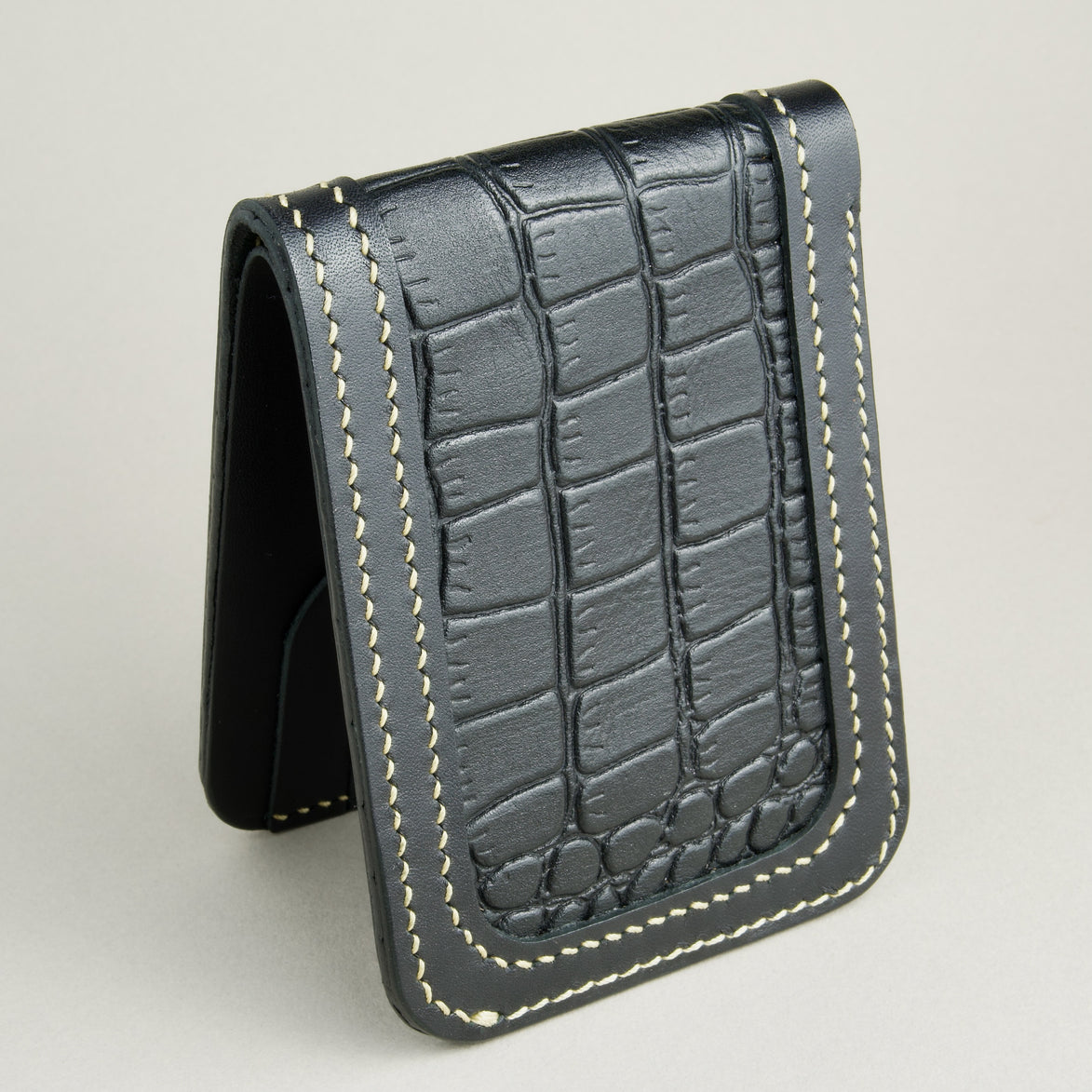 Top-down of obsidian black croc-embossed full-grain leather bifold wallet featuring ivory handmade stitching. Markore Indus Sultan
