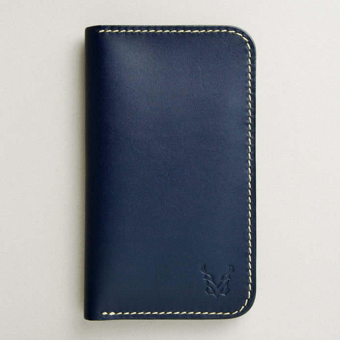 front view of vertical full-grain leather bifold wallet in dark blue, featuring handmade stitching in ivory and embossed logo. Markore Karakoram II.