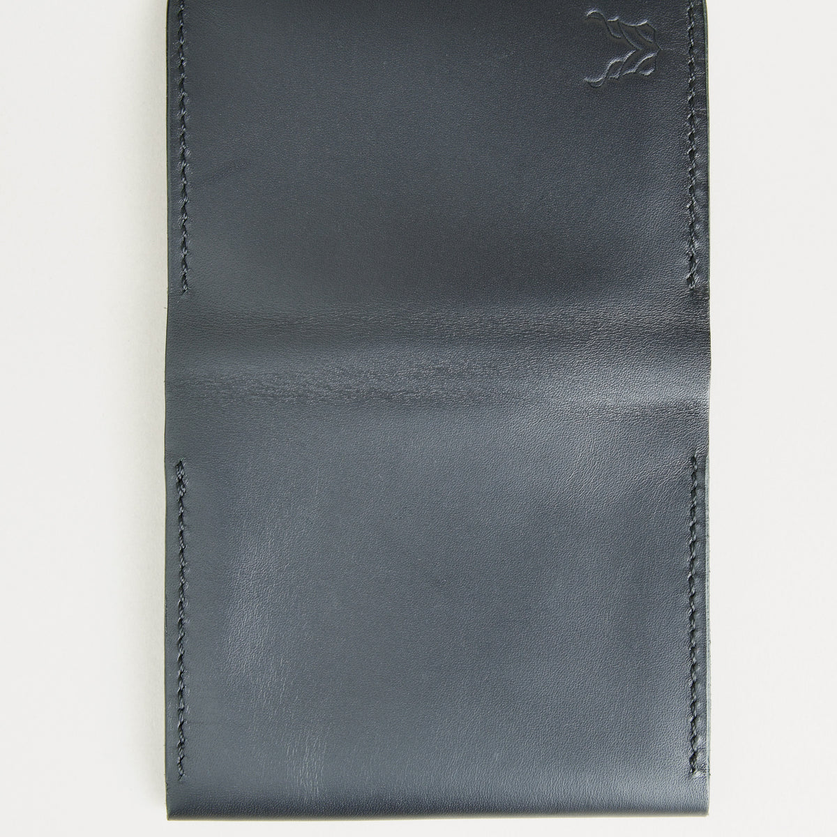 Outside view of midnight black full-grain leather flap fold wallet featuring handmade stitching and embossed logo. Markore Khaas Andaz.