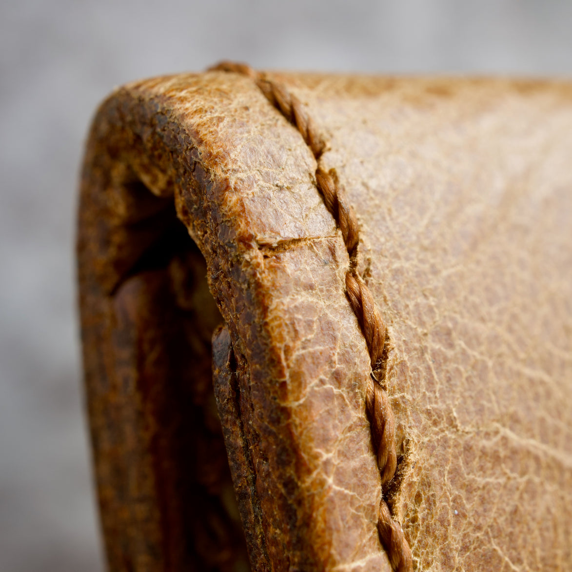 Close-up of a textured brown leather surface with handmade stitching