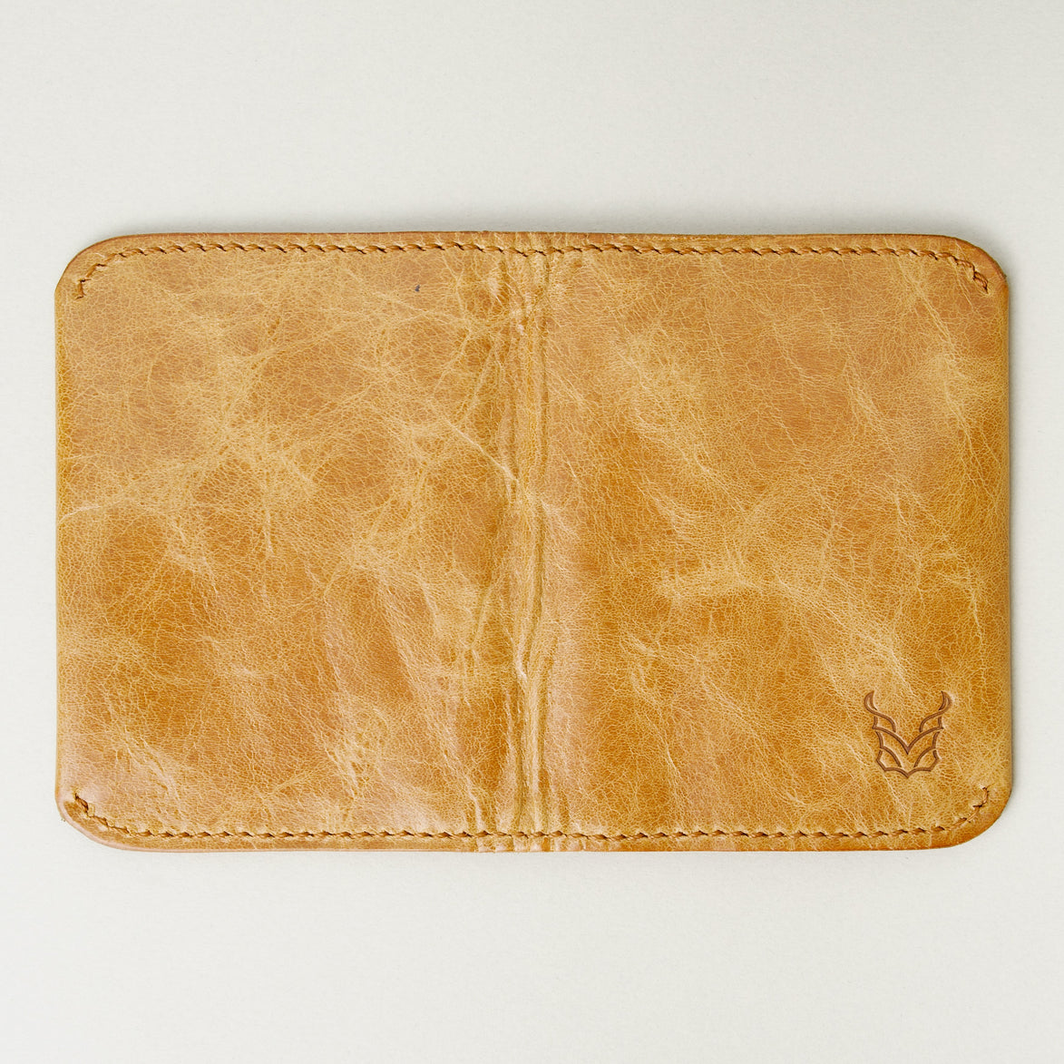 Back view of leather bifold wallet in natural, featuring handmade stitching and embossed logo. Markore Natural.