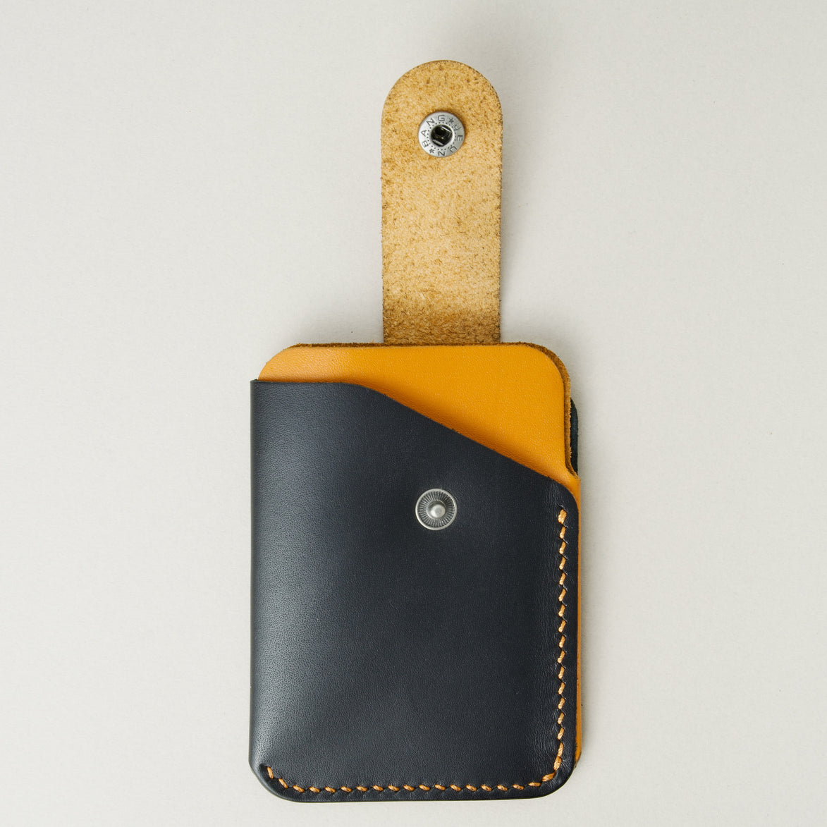 Front view of full grain leather card holder with open loop in midnight black and amber, featuring a leather loop with stainless steel press button and handmade stitching. Markore Niva Loop.