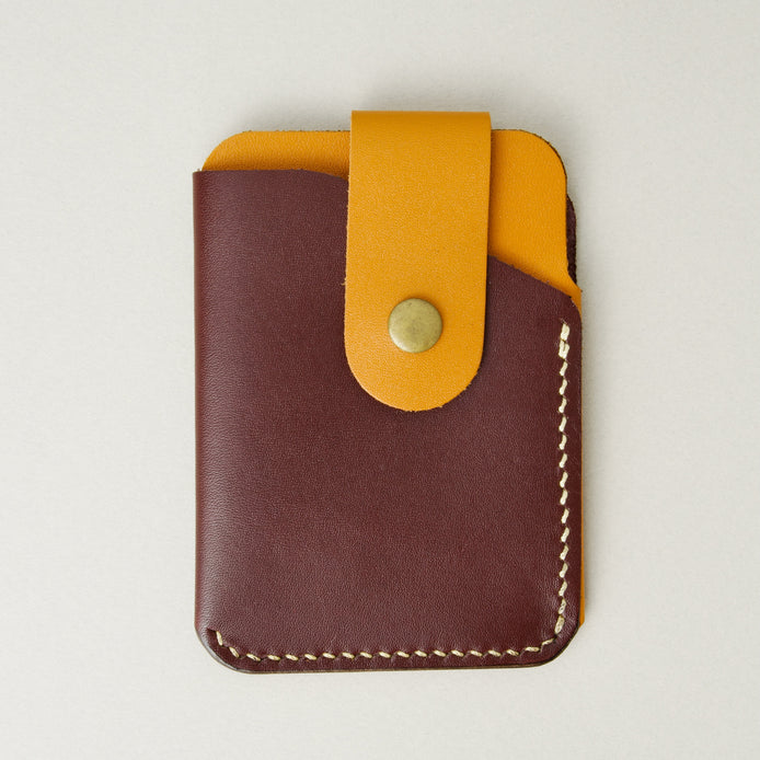 Front view of full grain leather card holder in espresso brown and amber, featuring a leather loop with brass press button and handmade stitching. Markore Niva Loop.