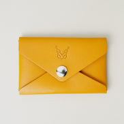 Front view of full grain leather envelope style wallet in amber with stainless steal press button and embossed logo. Markore Niva Seal.