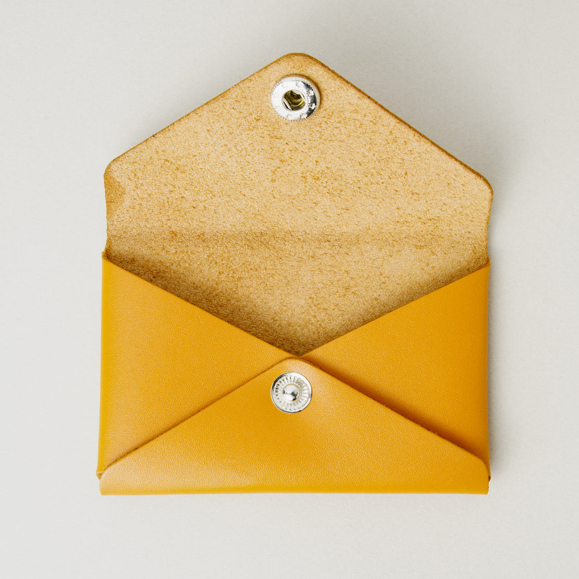 Front view of full grain leather envelope style wallet with open flap in amber with stainless steal press button. Markore Niva Seal.