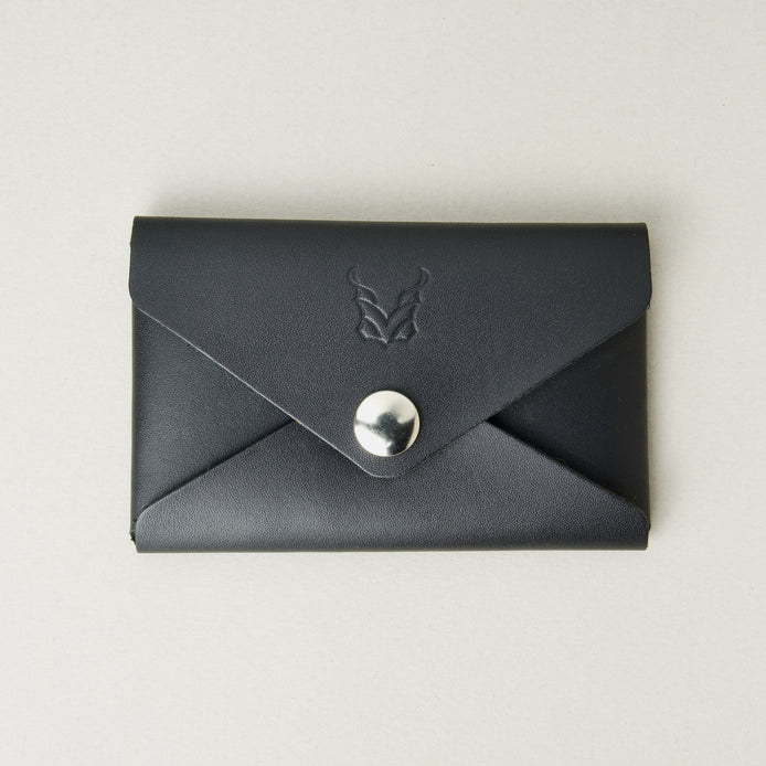 Front view of full grain leather envelope style wallet in midnight black with stainless steal press button and embossed logo. Markore Niva Seal.