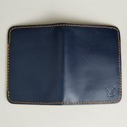 Outside view of dark blue full-grain leather wallet featuring amber handmade stitching, cross stitch detailing and embossed logo. Markore Ravi Edge