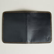 Outside view of midnight black full-grain leather vertical wallet featuring amber handmade stitching and embossed logo. Markore Ravi Fold.