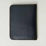 Back view of midnight black full-grain leather wallet featuring espresso brown handmade stitching. Markore Ravi Fold.