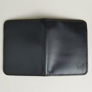 Outside view of midnight black full-grain leather vertical wallet featuring espresso brown handmade stitching and embossed logo. Markore Ravi Fold.