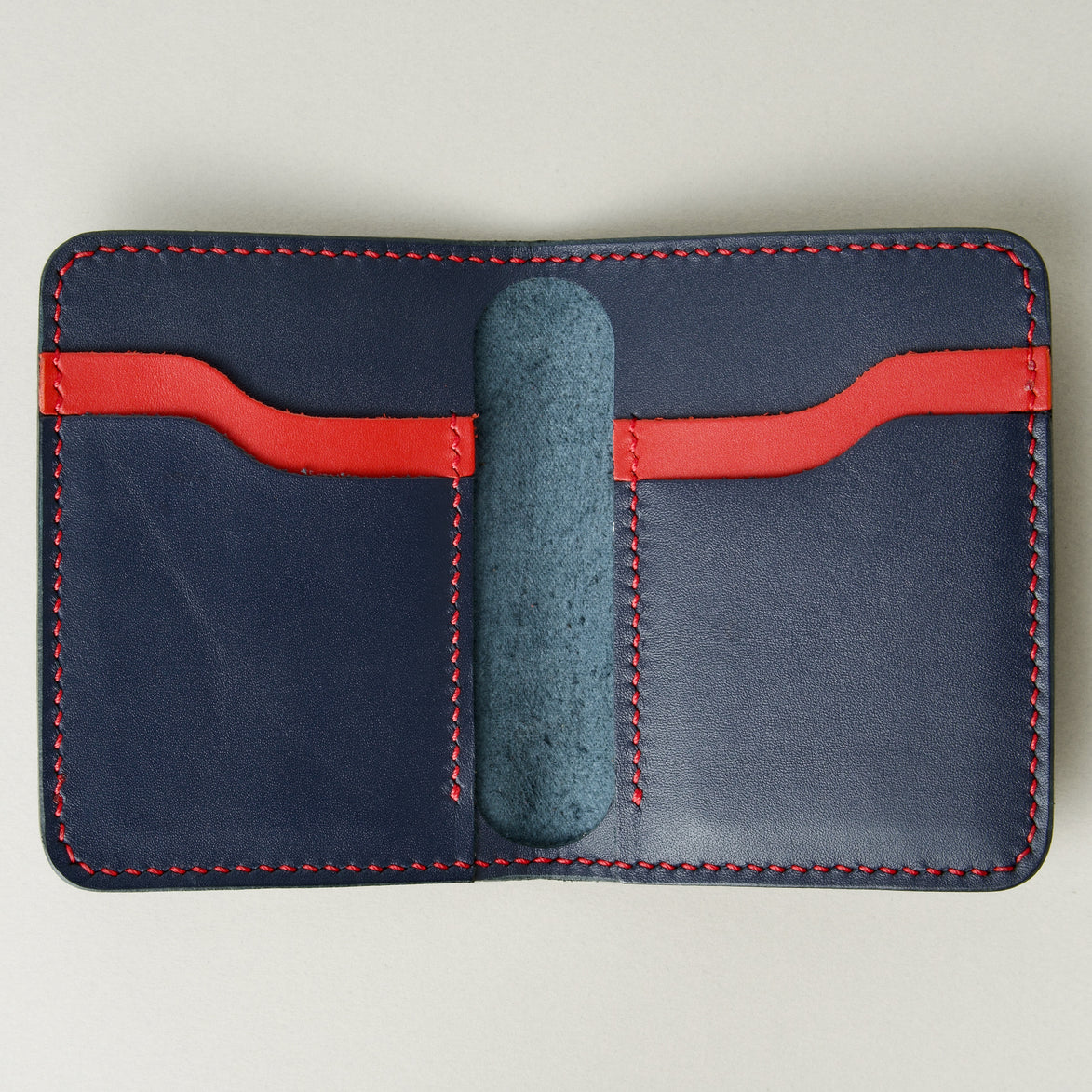 Inside view of dark blue full-grain leather wallet featuring red and blue card slots and red handmade stitching. Markore Ravi Fold.