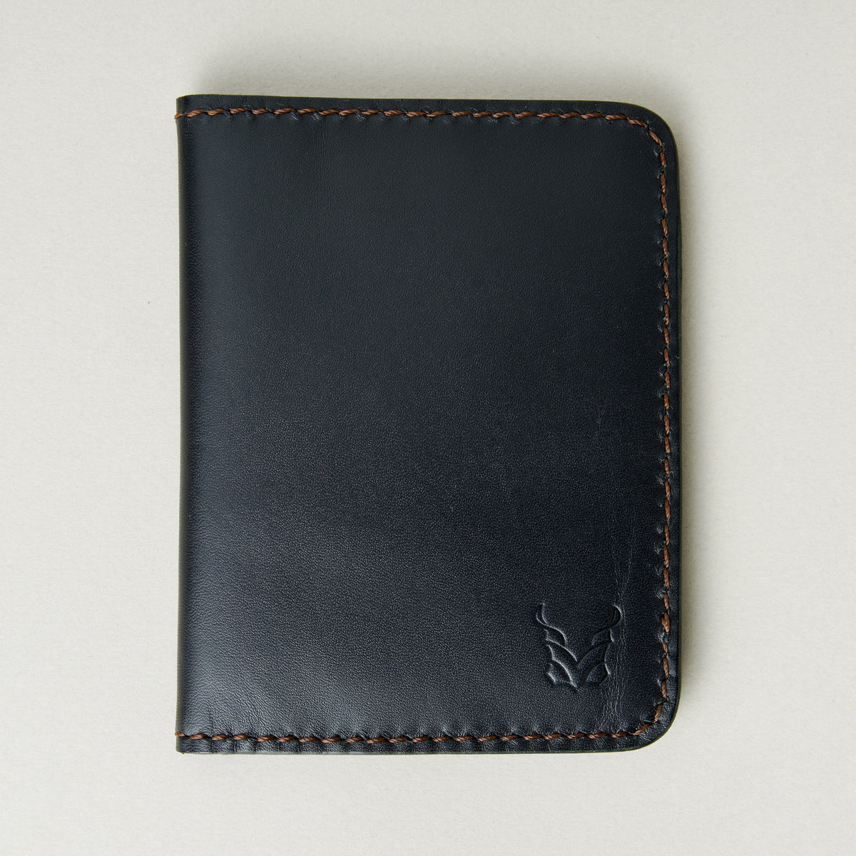 Front view of midnight black full-grain leather wallet featuring espresso brown handmade stitching and embossed logo. Markore Ravi Fold.