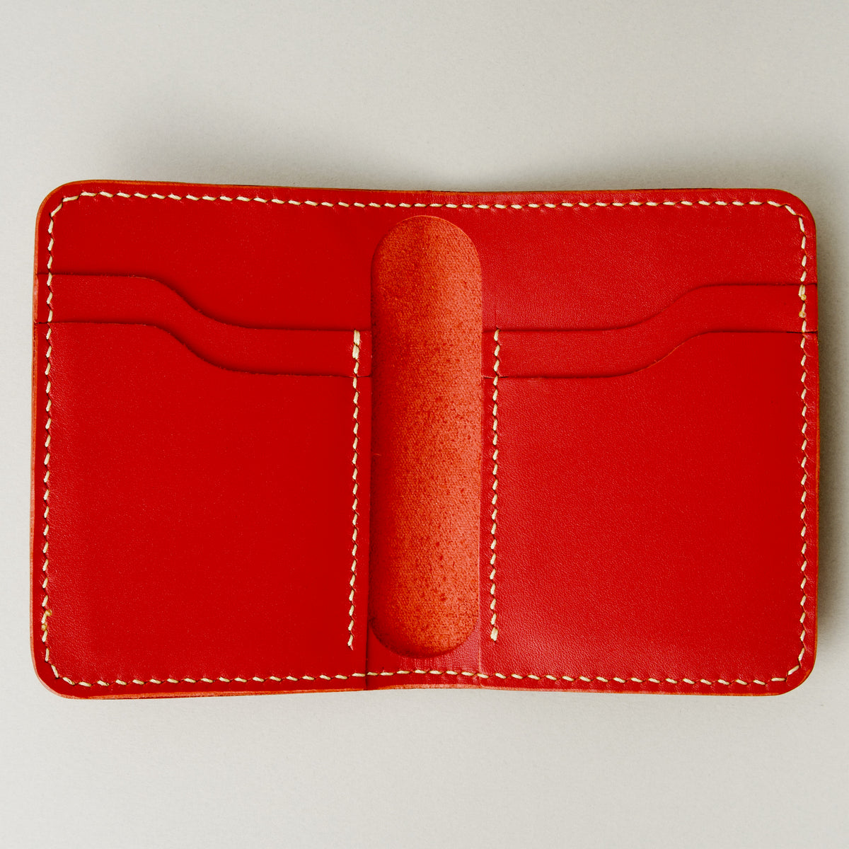 Inside view of red full-grain leather wallet featuring card slots and ivory handmade stitching. Markore Ravi Fold.