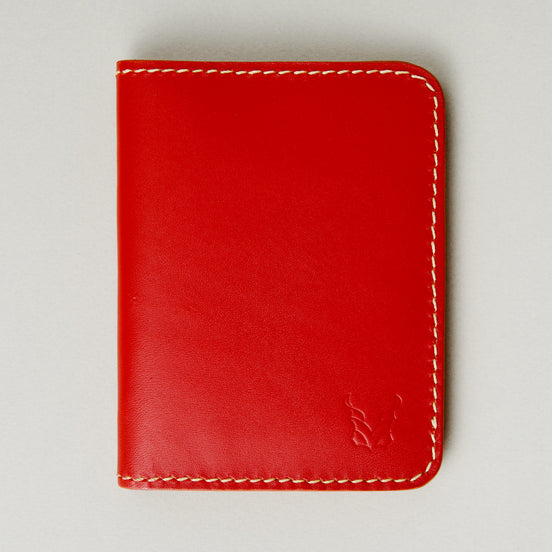 Front view of red full-grain leather wallet featuring ivory handmade stitching and embossed logo. Markore Ravi Fold.