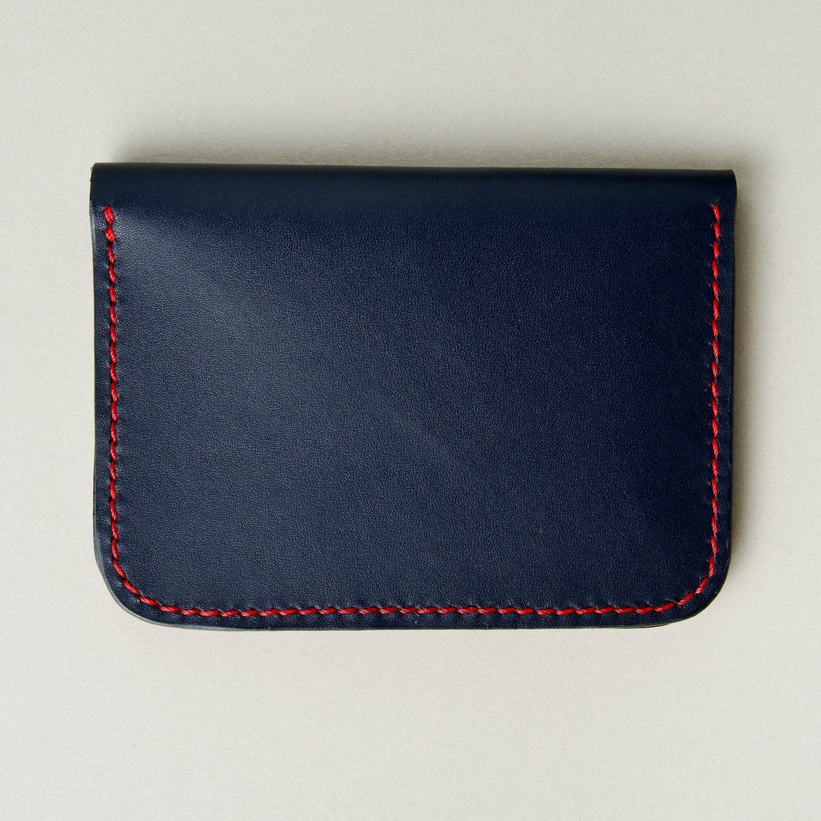 Back view of dark blue full-grain leather wallet featuring red handmade stitching. Markore Ravi Slip.