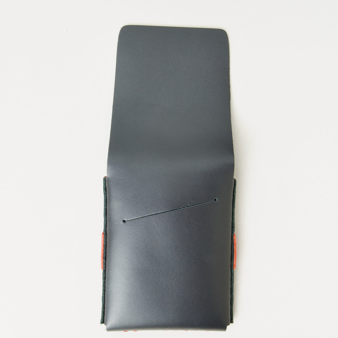 Back view of midnight black full-grain leather flap wallet with open flap featuring a card slot, and red handmade stitching. Markore Sutlej Vault.