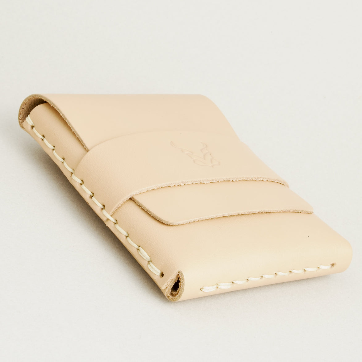 Bottom side view of natural full-grain leather flap wallet featuring a flap holder with embossed logo, and handmade stitching. Markore Sutlej Vault.