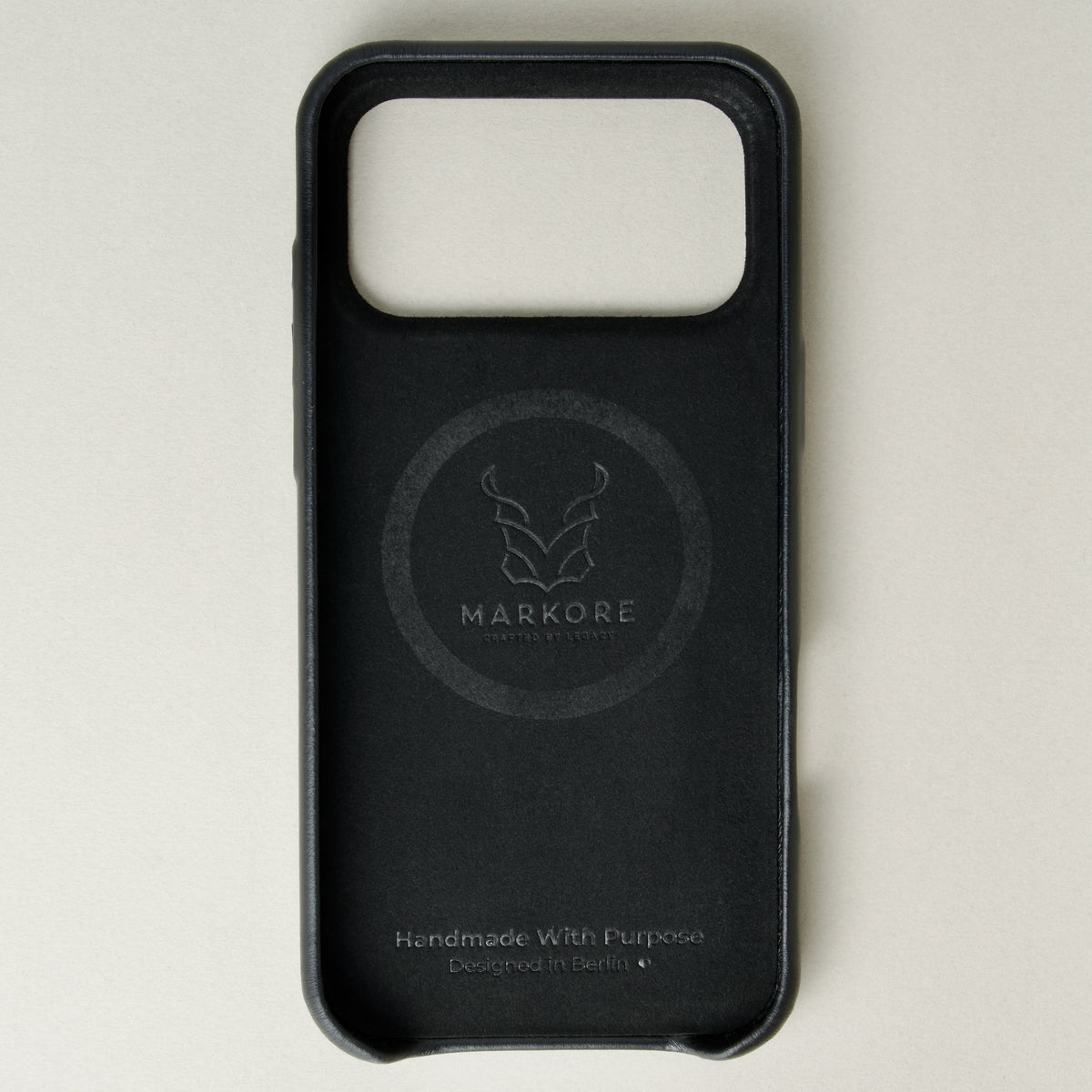 Inside view of midnight black leather iphone 17 pro case with full cutout showing velvet lining and brand logo. Markore Shell Frame.