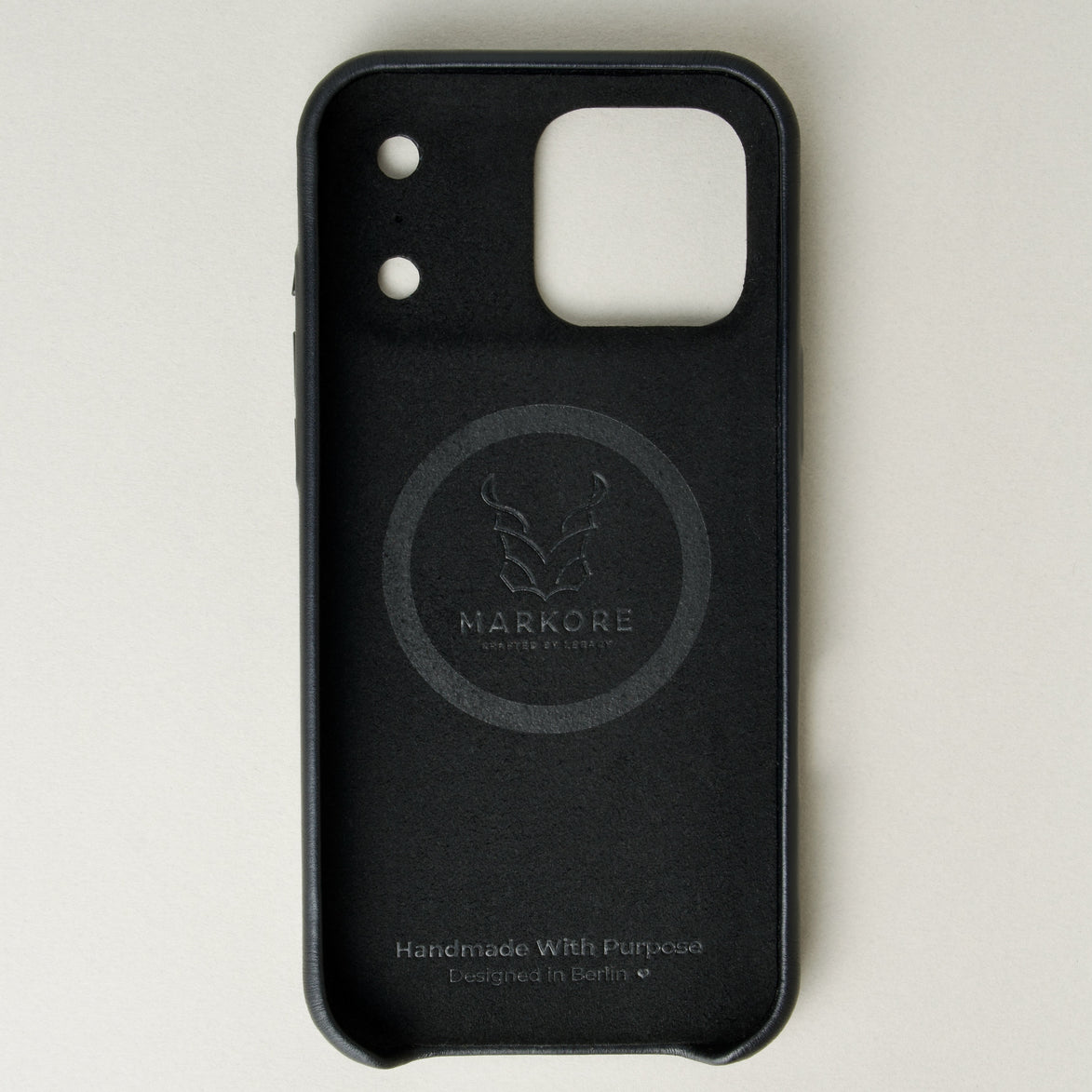 Inside view of midnight black leather iPhone 17 pro cover with camera cutout showing velvet lining with brand logo and inscription. Markore Shell Guard.