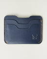 Front view of dark blue full-grain leather card sleeve featuring card slots, amber handmade stitching and embossed logo. Markore Niva Zoj.