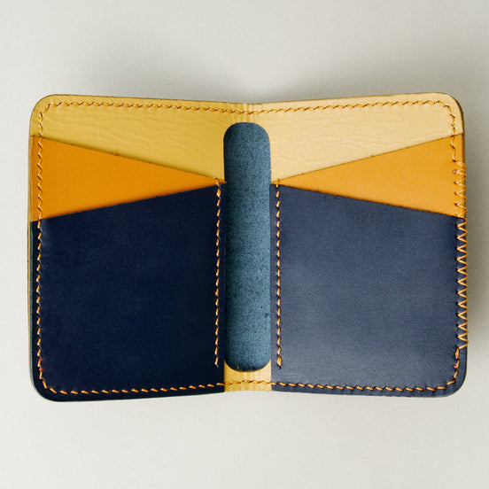 Inside view of dark blue full-grain leather wallet revealing tri-tone interior pockets in tan, amber and dark blue, card slots and handmade stitching. Markore Ravi Edge.