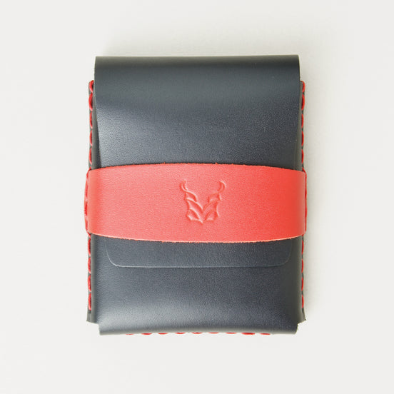 Front view of midnight black full-grain leather flap wallet featuring a red flap holder with embossed logo, and red handmade stitching. Markore Sutlej Vault.