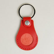 Front view of red AirTag keychain in full-grain leather with round metal key ring and stainless steel press stud. Markore Tag Mate.