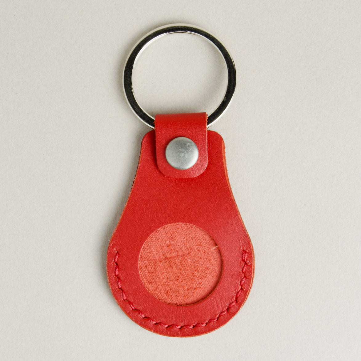 Front view of red AirTag keychain in full-grain leather with round metal key ring and stainless steel press stud. Markore Tag Mate.