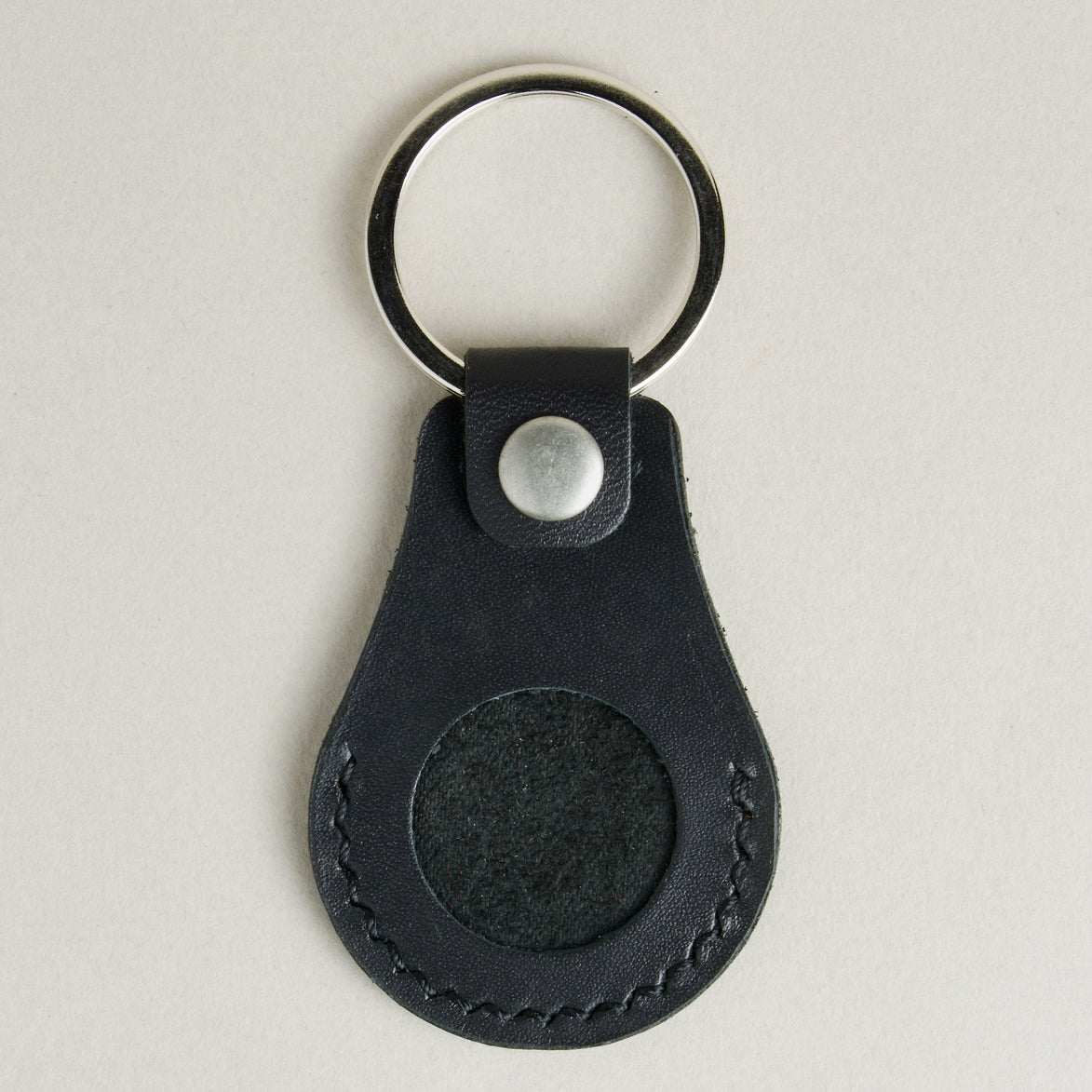 Front view of midnight black AirTag keychain in full-grain leather with round metal key ring and stainless steal press stud. Markore Tag Mate.